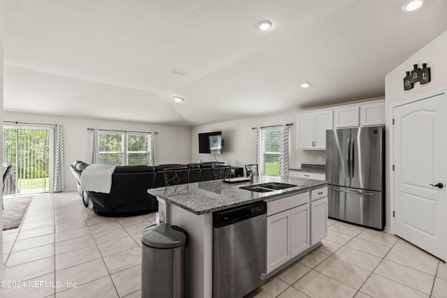 kitchen with white cabinets, lofted ceiling, stainless steel appliances, and a kitchen island with sink