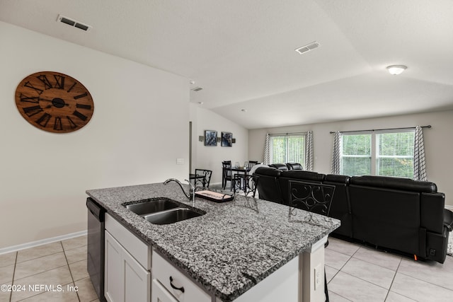 kitchen with vaulted ceiling, sink, light tile patterned floors, white cabinetry, and an island with sink