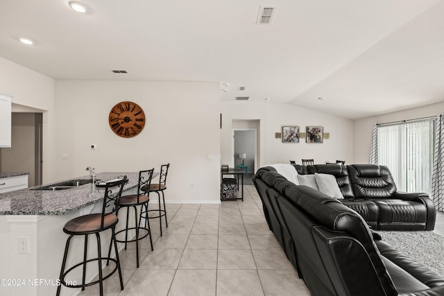 living room with light tile patterned flooring, vaulted ceiling, and sink