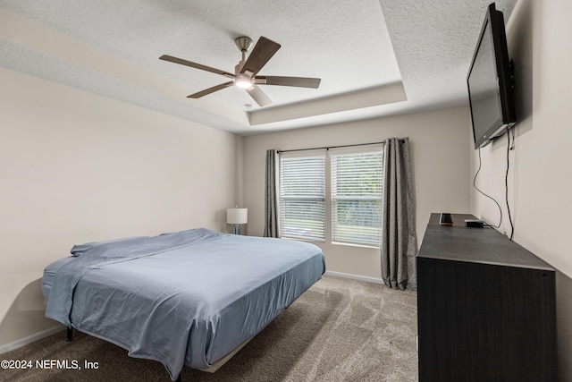 carpeted bedroom featuring ceiling fan, a raised ceiling, and a textured ceiling