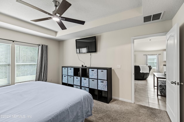 bedroom featuring multiple windows, ceiling fan, light colored carpet, and a textured ceiling