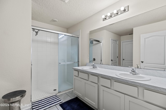 bathroom with tile patterned floors, a shower with door, vanity, and a textured ceiling