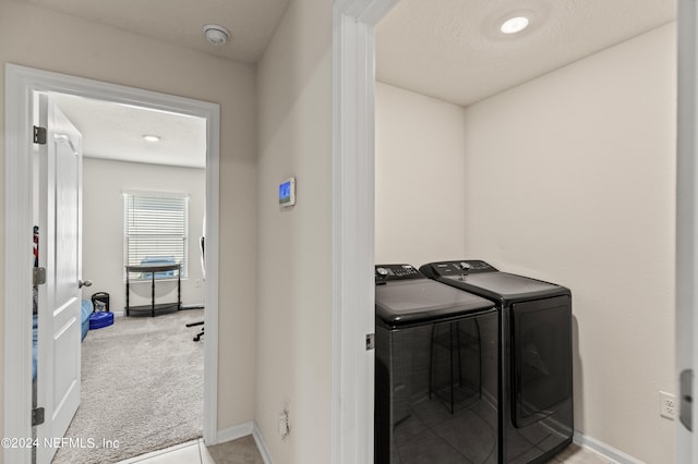 washroom with washer and clothes dryer, light colored carpet, and a textured ceiling