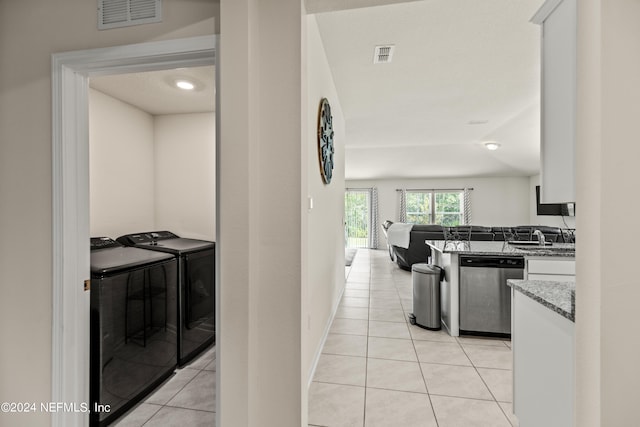 kitchen featuring white cabinets, light tile patterned floors, separate washer and dryer, and stainless steel dishwasher