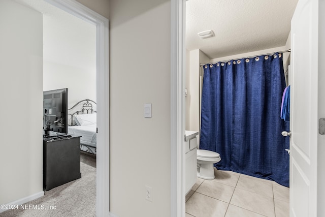 bathroom with tile patterned flooring, a textured ceiling, vanity, and toilet