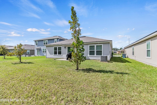 rear view of property with a yard and central AC