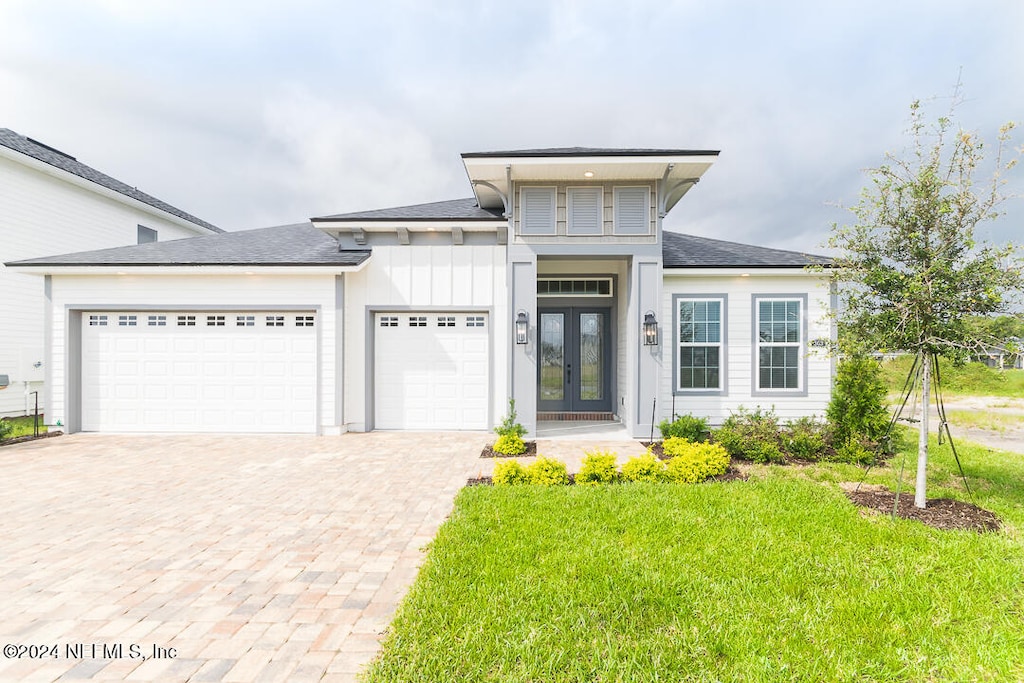 prairie-style home with a front yard, french doors, and a garage