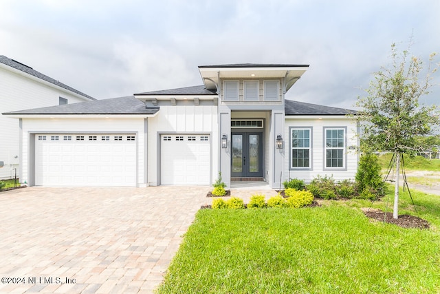 prairie-style home with a front yard, french doors, and a garage