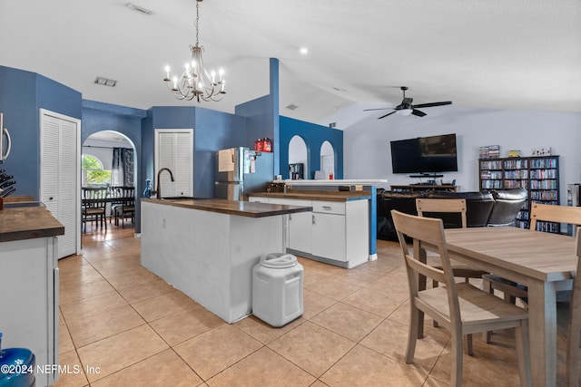 kitchen with pendant lighting, white cabinets, vaulted ceiling, butcher block countertops, and stainless steel appliances