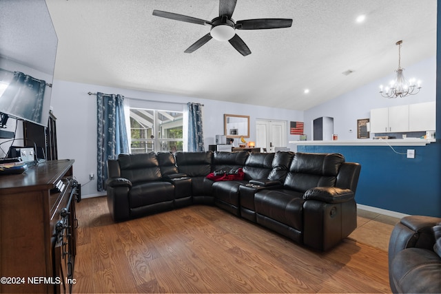 living room with wood-type flooring, ceiling fan with notable chandelier, a textured ceiling, and vaulted ceiling