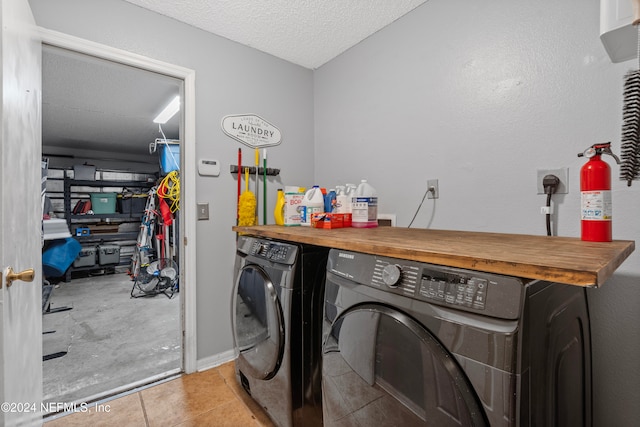 laundry room with light tile patterned floors, a textured ceiling, and independent washer and dryer