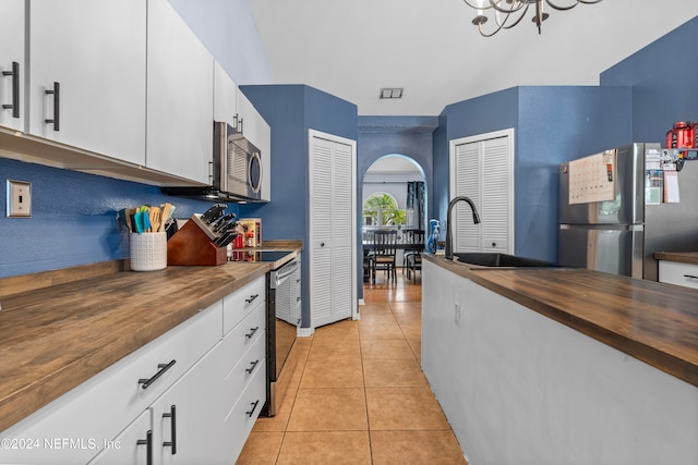 kitchen with wooden counters, stainless steel appliances, and white cabinetry