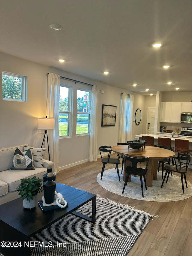 living area with baseboards, light wood-type flooring, and recessed lighting