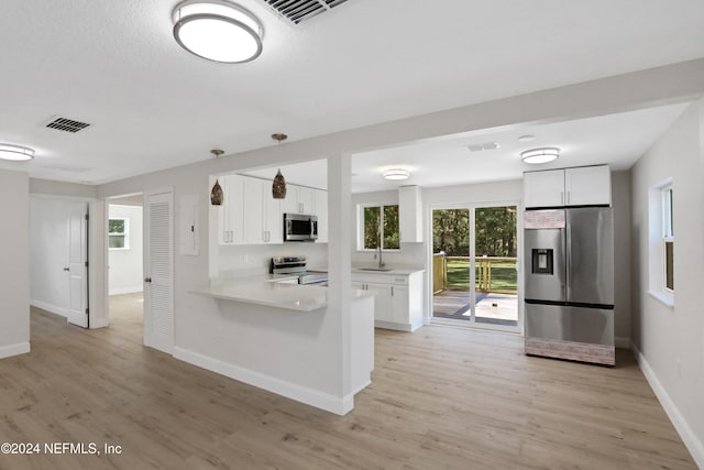 kitchen with white cabinets, sink, hanging light fixtures, appliances with stainless steel finishes, and kitchen peninsula