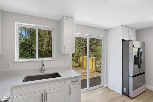 kitchen with white cabinetry, stainless steel fridge with ice dispenser, light hardwood / wood-style flooring, and sink