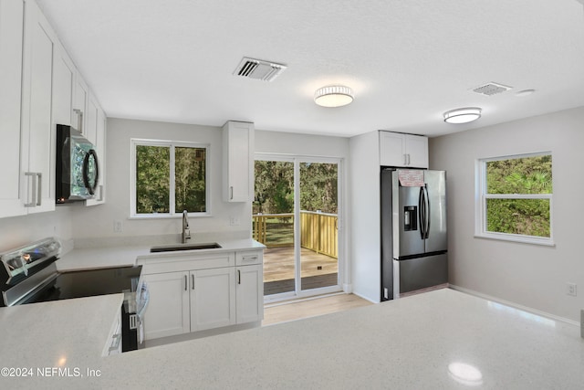 kitchen featuring a wealth of natural light, white cabinetry, sink, and stainless steel appliances