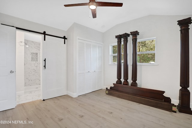 entrance foyer with a barn door, light hardwood / wood-style floors, vaulted ceiling, and ceiling fan