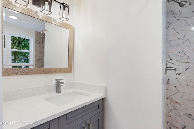 bathroom with a tile shower and vanity