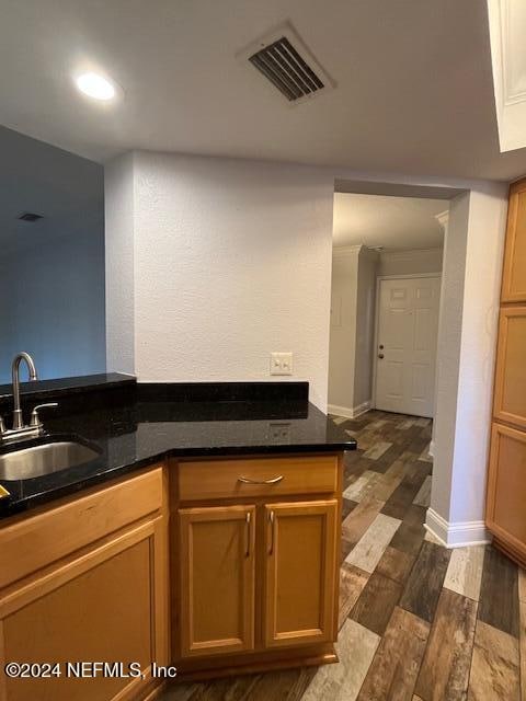 kitchen featuring kitchen peninsula, sink, dark stone counters, and dark hardwood / wood-style floors