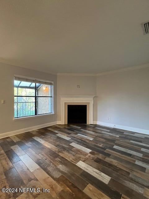 unfurnished living room featuring ornamental molding and dark wood-type flooring