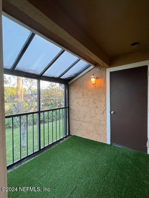 unfurnished sunroom featuring beam ceiling and a wealth of natural light