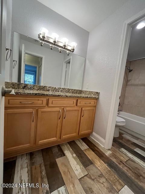 full bathroom with hardwood / wood-style floors, vanity, toilet, and tiled shower / bath combo