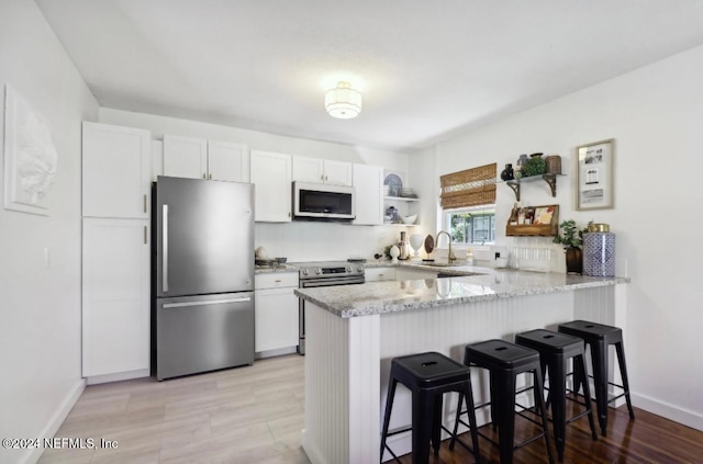 kitchen with kitchen peninsula, stainless steel appliances, and white cabinets