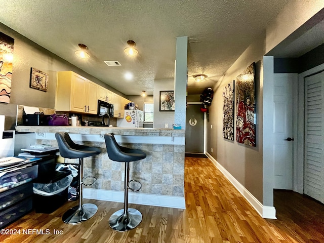 650 Pope Rd W Unit 251, Saint Augustine, FL 32080 - kitchen with refrigerator, a textured ceiling, black microwave, wood finished floors, and light countertops