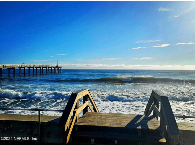 view of dock with a beach view and a water view