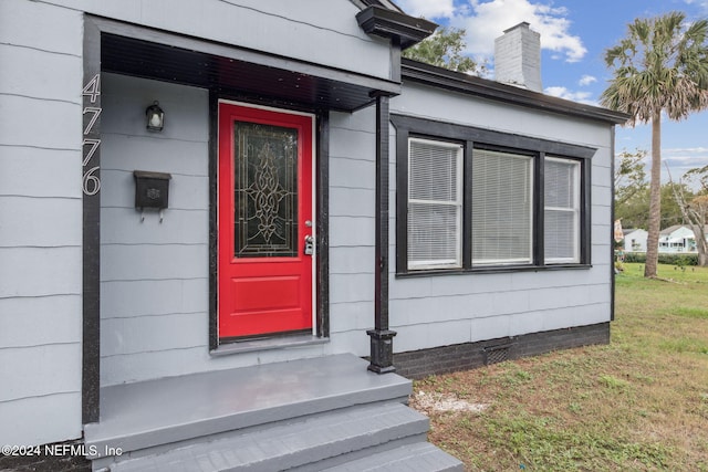 doorway to property with a lawn