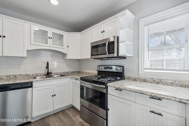 kitchen with light stone counters, stainless steel appliances, sink, dark hardwood / wood-style floors, and white cabinetry