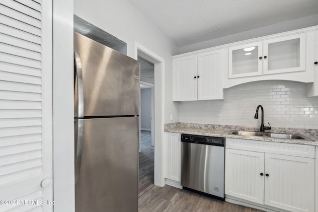 kitchen featuring dark wood-type flooring, white cabinets, sink, light stone countertops, and appliances with stainless steel finishes