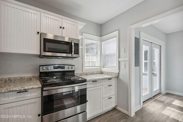 kitchen featuring white cabinetry, french doors, decorative backsplash, appliances with stainless steel finishes, and light wood-type flooring