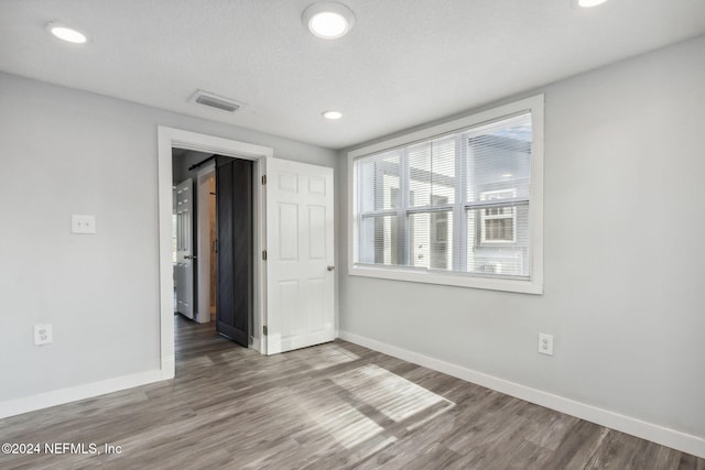 empty room with wood-type flooring and a textured ceiling