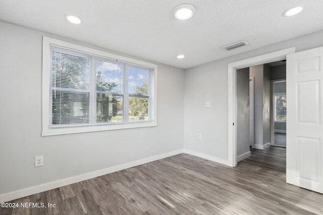 empty room with plenty of natural light, dark hardwood / wood-style flooring, and a textured ceiling