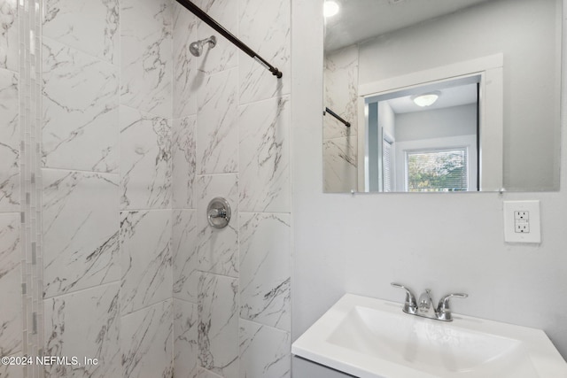 bathroom with a tile shower and vanity