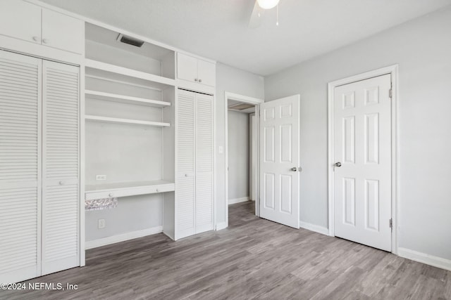 unfurnished bedroom featuring light wood-type flooring, two closets, and ceiling fan