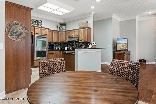 7436 Woodlawn Rd, Macclenny, FL 32063 - kitchen featuring light wood-type flooring, backsplash, ornamental molding, a textured ceiling, and stainless steel double oven