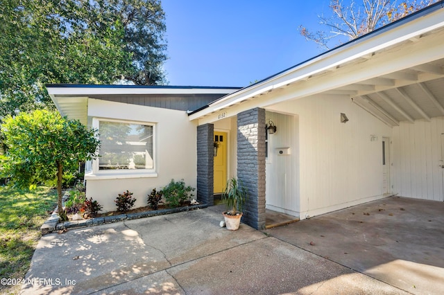 entrance to property featuring driveway and an attached carport