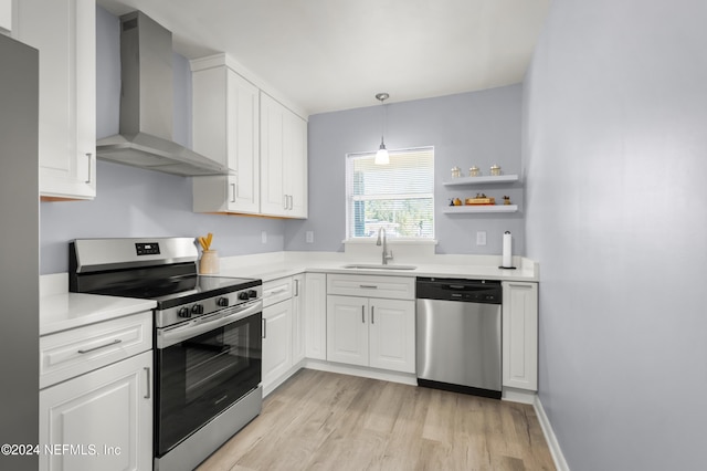 kitchen featuring light countertops, appliances with stainless steel finishes, wall chimney range hood, and white cabinets