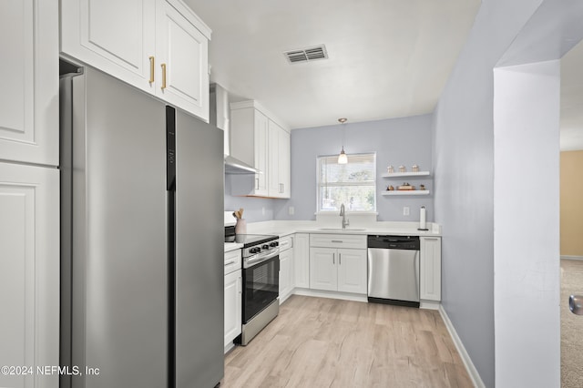 kitchen featuring light countertops, hanging light fixtures, appliances with stainless steel finishes, white cabinets, and a sink