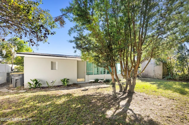 back of house featuring a lawn, fence, and stucco siding