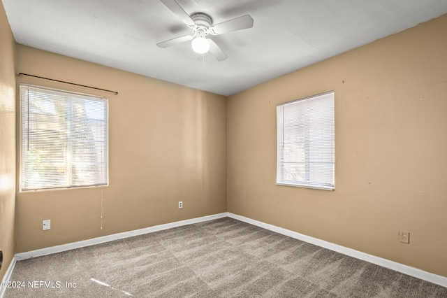 carpeted spare room with ceiling fan and baseboards