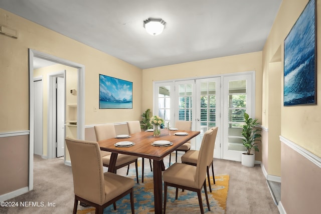 dining area with light carpet, french doors, and baseboards