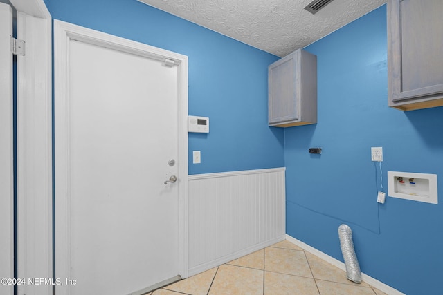 laundry area featuring cabinets, washer hookup, a textured ceiling, hookup for an electric dryer, and light tile patterned flooring