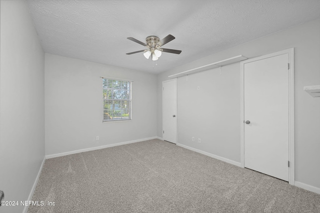 spare room with a textured ceiling, carpet floors, and ceiling fan