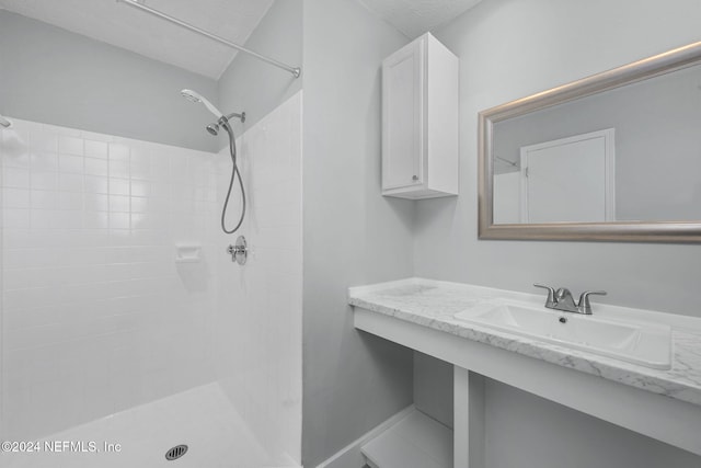 bathroom with tiled shower and sink