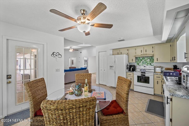 kitchen with a textured ceiling, white appliances, sink, light tile patterned floors, and cream cabinetry