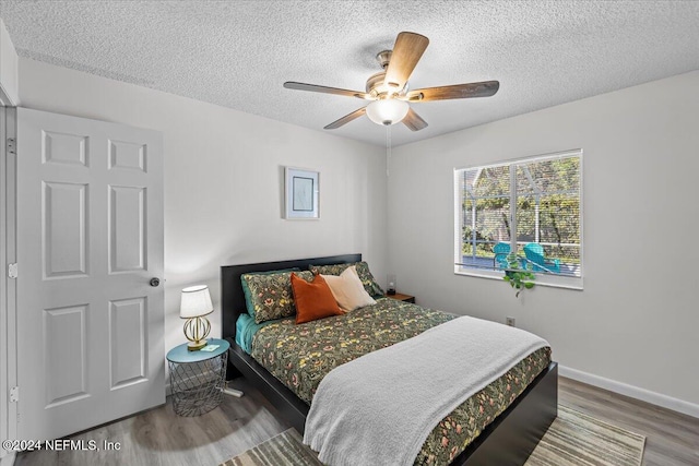 bedroom with ceiling fan, wood-type flooring, and a textured ceiling