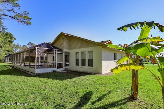 rear view of property with a lanai and a lawn